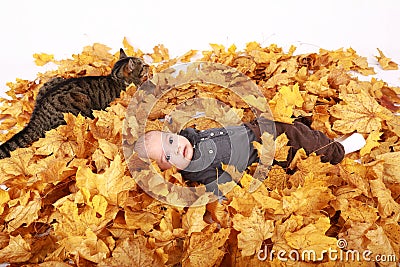 Tabby cat lying aside surprised baby boy lying in leaves Stock Photo