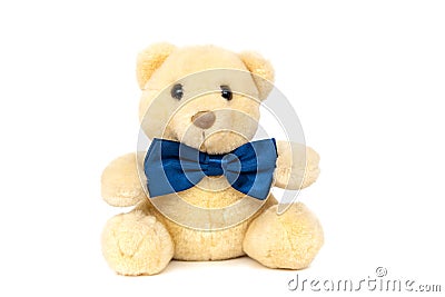 Cute teddy bear with blue bow tie sitting at white wall Stock Photo