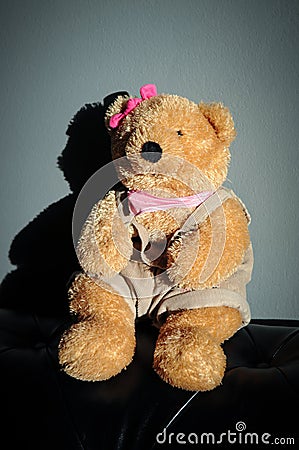 Cute Teddy bear female doll toy is sitting on old vintage sofa Stock Photo