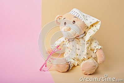 Cute teddy bear and pink baby glasses on beige and pink background Stock Photo