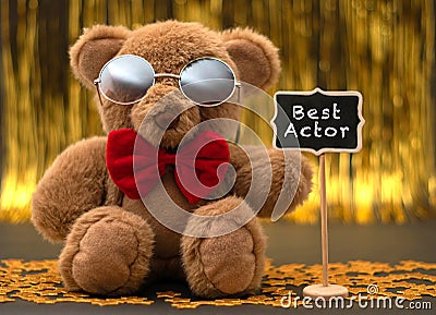 Cute teddy bear with red bow and sunglasses. Little chalkboard with `Best Actor` written whit white chalk Stock Photo