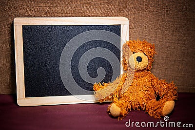 Cute teddybear sitting next to chalkboard Stock Photo
