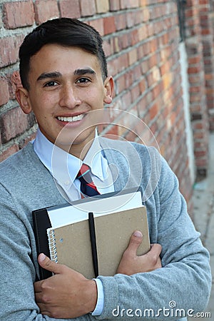 Cute teenager boy in formal high school uniform holding notebooks smiling Stock Photo