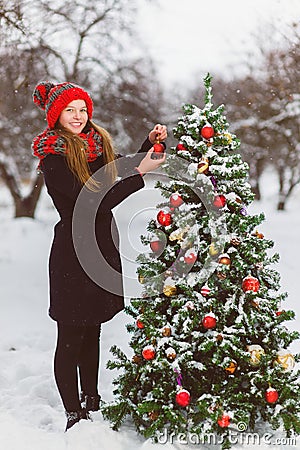 Cute teenager or girl decorating christmas tree outdoor Stock Photo