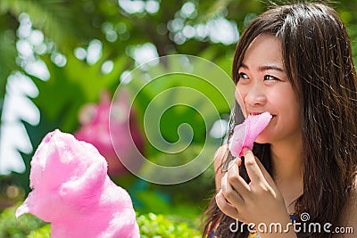 Cute Thai girl is eating pink candyfloss Stock Photo