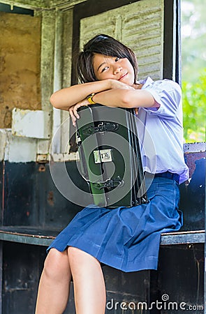 Cute Thai schoolgirl is daydreaming in an old bus stop Stock Photo