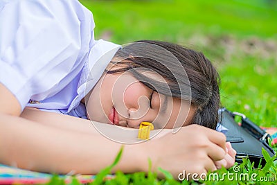 Cute Thai schoolgirl fall asleep during doing outdoor homework Stock Photo