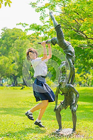 Cute Thai schoolgirl is jumping with a statue Stock Photo