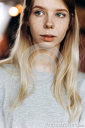 A cute thin beautiful girl,wearing casual style,looks somewhere attentively in a modern coffee shop. Stock Photo