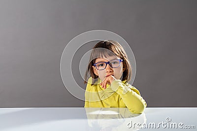 Cute thinking child with eyeglasses enjoying thinking, looking at camera Stock Photo