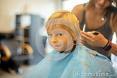 Cute toddler blond boy, having haircut in hairdresser salloon Stock Photo