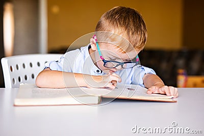 Cute toddler boy with down syndrome with big glasses reading intesting book Stock Photo