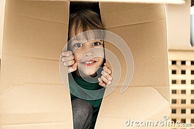 Cute toddler boy playing in cardboard box at new home. Stock Photo
