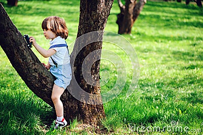 Cute toddler child boy with long hair in stylish outfit playing with toy car on the walk in summer Stock Photo