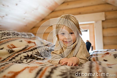 Cute toddler child in a little fancy wooden cottage, reading a book, drinking tea Stock Photo