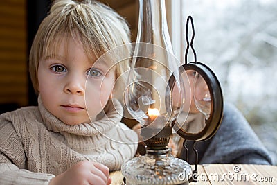 Cute toddler child in a little fancy wooden cottage, reading a book, drinking tea Stock Photo