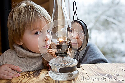 Cute toddler child in a little fancy wooden cottage, reading a book, drinking tea Stock Photo