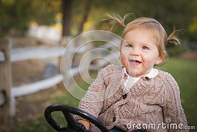 Cute Toddler Laughing and Playing on Toy Tractor Outside Stock Photo
