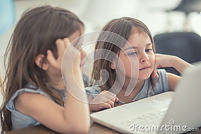 Cute twins little sisters usin modern laptop Stock Photo