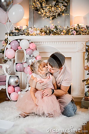 Cute view of beautiful little girl with her father against background of New Year`s decorations Stock Photo