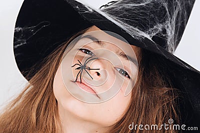 Girl`s face in witch hat with spider halloween direct look Stock Photo