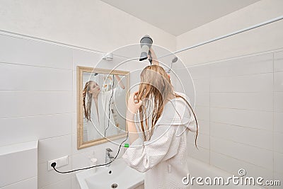 Cute woman dries her hair with a hair dryer after shower Stock Photo