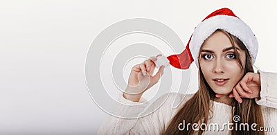 Cute woman looking at camera and toching her christmas hat Stock Photo