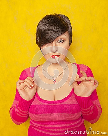 Cute woman with short hair dressed in a pink cozy sweater plays with a large long roll of bubble gum Stock Photo