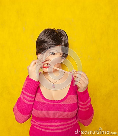 Cute woman with short hair dressed in a pink cozy sweater plays with a large long roll of bubble gum Stock Photo