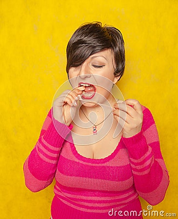 Cute woman with short hair dressed in a pink cozy sweater plays with a large long roll of bubble gum Stock Photo