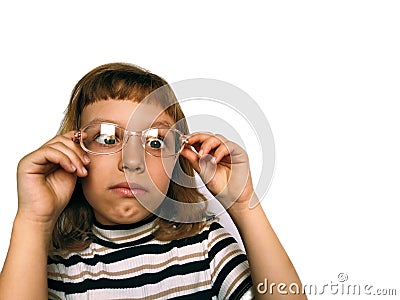 Cute 7 year old Caucasian girl looks into glasses. Eyes in a bunch. Ophthalmic problems in children. Myopia, exophoria and Stock Photo