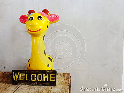 Ceramic giraffe with welcome sign on wooden background Stock Photo