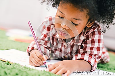 Cute young African American kid girl drawing or painting with colored pencil Stock Photo