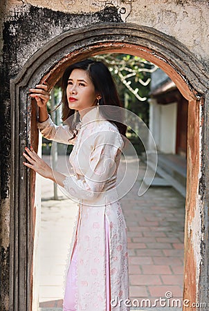 Cute young Asian woman standing at arched passage of ancient building Stock Photo