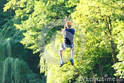Cute young boy in helmet with climbing equipment in the rope amusement park. Summer camp, Stock Photo
