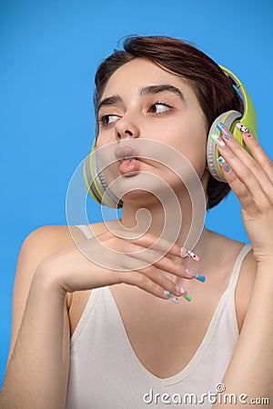Cute young brunette making fish lips while listening music using wireless headphones Stock Photo