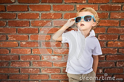 Cute Young Caucasian Boy in Sunglasses Against Brick Wall Stock Photo