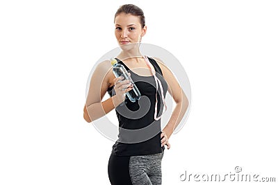 Cute young girl in fitness black t-shirt looks away and keeps the shoulder strap and a bottle of water in hand Stock Photo