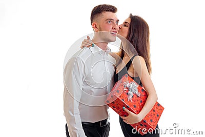 Cute young girl holding a gift and kisses the handsome guy smiling Stock Photo