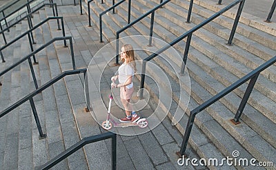 Cute young woman with a pink kick scooter on the stairs, top view, minimalist photo. Copyspace Stock Photo