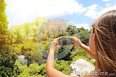 Cute young woman takes a picture of the Acropolis, Athens, Greece. Famous ancient Greek Acropolis is the main landmarks of Athens Stock Photo