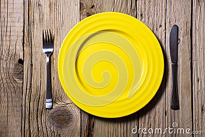 Cutlery and yellow plate on wooden Stock Photo