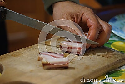 Cutting bacon into large pieces Stock Photo