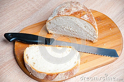 Cutting board, bread and a knife lying on a wooden table Stock Photo