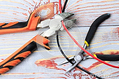 Cutting cable with pliers, on a wooden background in the old style, there is toning, close-up Stock Photo