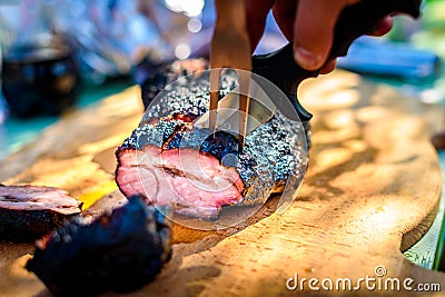 Cutting delicious roast beef pork meat from slow cooking smoker. Stock Photo