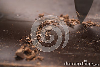 Cutting industrial block of dark chocolate with knife Stock Photo