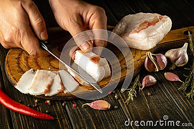 Cutting lard into small pieces before preparing sandwiches for snacks. National Ukrainian food. Peasant products. Male hands with Stock Photo