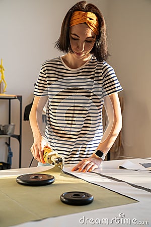 Cutting and sewing in tailor studio: sewer young woman work with fabric in design workshop studio Stock Photo
