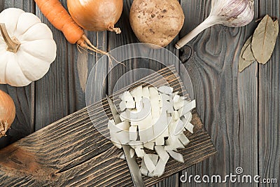 Cutting white spicy onion with knife into cubes on kitchen wooden board. White diced onion. Flat lay view. Healthy food. Stock Photo